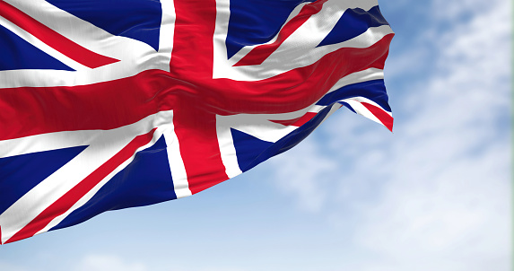 Close-up view of the United Kingdom flag waving in the wind. The United Kingdom is an island state in Western Europe . Fabric textured background. Selective focus.