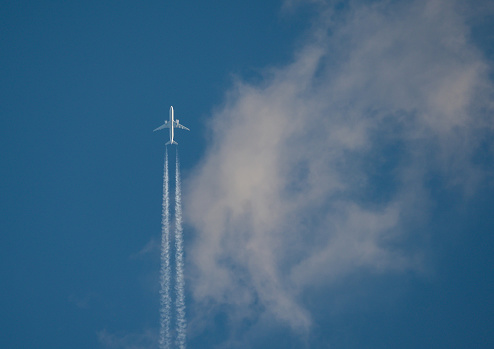 The airliner flies at high altitude, among the clouds.