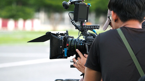 Behind the scenes of movie shooting or video production and film crew team with camera equipment at outdoor location.