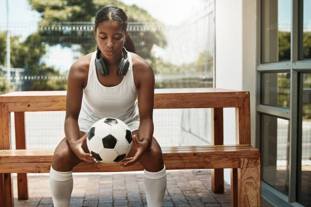 kobieta, piłkarz i myślenie o golach meczowych, strategii gry i ćwiczeniach sportowych w przerwie fitness. piłka nożna, piłka nożna i pomysły na trening, trening lub wellness ze słuchawkami motywacyjnymi - soccer bench soccer player sport zdjęcia i obrazy z banku zdjęć