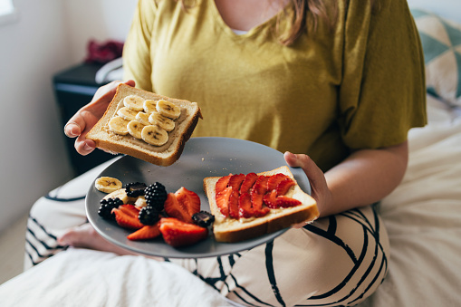 Anonymous woman holding a plate with her breakfast on it.
