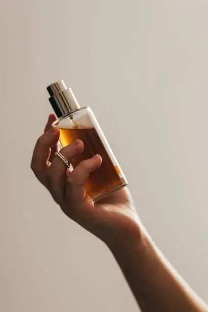 Close up shot of an anonymous woman holding a bottle of perfume.