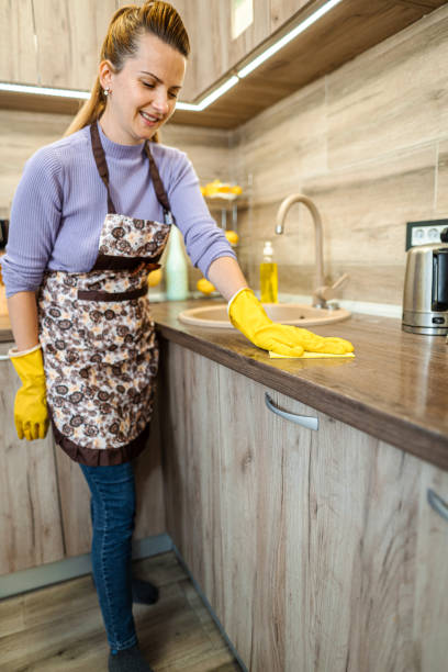 frau mit gelben reinigungsmitteln reinigt eine arbeitsplatte. - cleaning domestic kitchen counter top housework stock-fotos und bilder