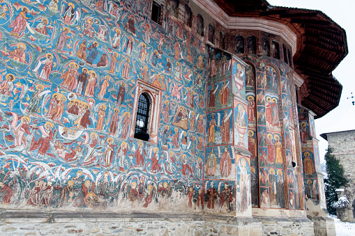 Moldovita, Romania, 2021-12-29. Moldovita Monastery, in the Bukovina region. Its exterior walls are composed of frescoes painted in the 15th and 16th centuries, representing portraits of saints and prophets, scenes from the life of Jesus, images of angels and demons, of heaven and hell.