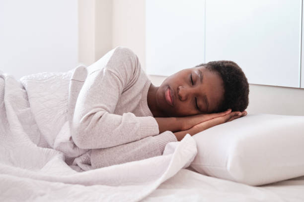 istock Black female sleeping in bed with hands under head 1444512057