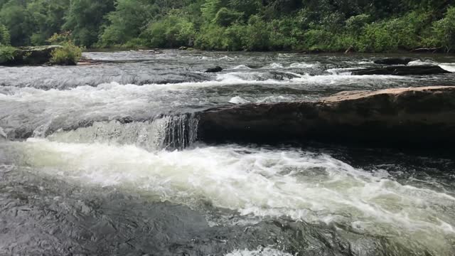 Slow motion clip of the Chattooga River and waterfalls flowing in the rain pan to upstream