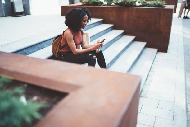 istock Positive black lady browsing cellphone in street 1444517044