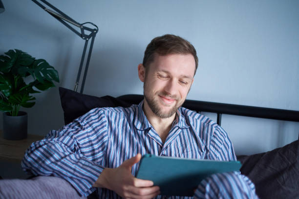 istock Online shopping concept: man sitting on bed using tablet for shopping 1444517883