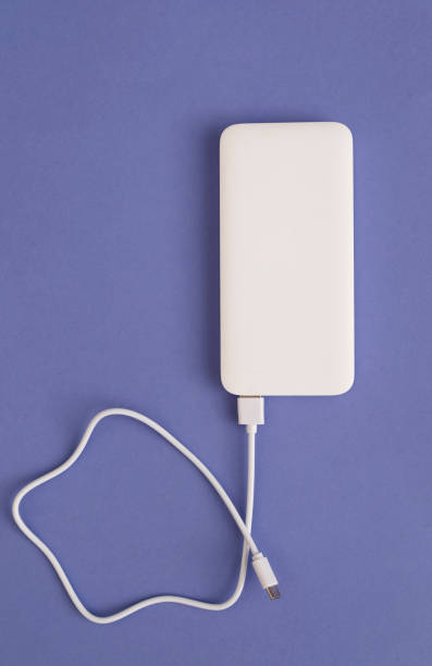 White Power Bank with USB Cable on purple Background Top View White Power Bank with USB Cable on purple Background Top View. phone charger cable stock pictures, royalty-free photos & images