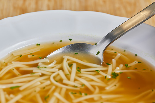 Close up of a homemade vegetable soup, on a light wooden kitchen table top with a free space for copy