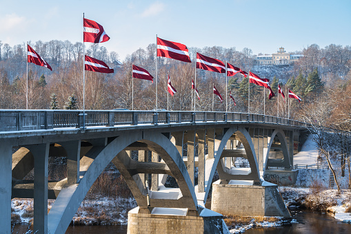 Sigulda, Latvia - November 20, 2022: The bridge across the Gauja river decorated with the national flags of Latvia