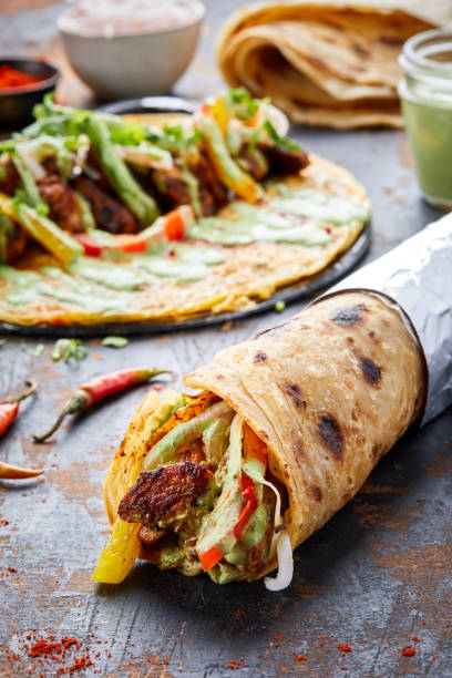 istock Chicken Tikka paratha roll kathi shawarma wrap with dipping sauce isolated on background side view of indian fastfood 1444527484