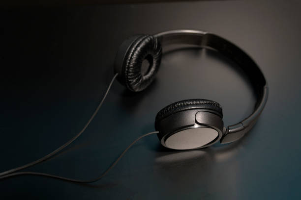 istock black headphones with a wire lying on a black reflective surface 1444531511
