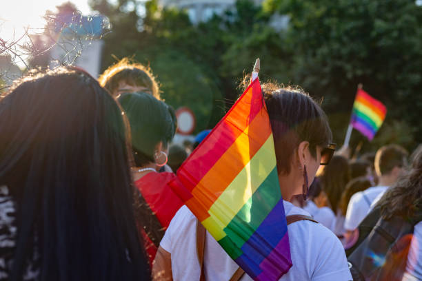 Rear view of female pride parade attendee carrying a rainbow flag Madrid Spain. July 9, 2022. Rear view of female pride parade attendee carrying a rainbow flag human rights act stock pictures, royalty-free photos & images