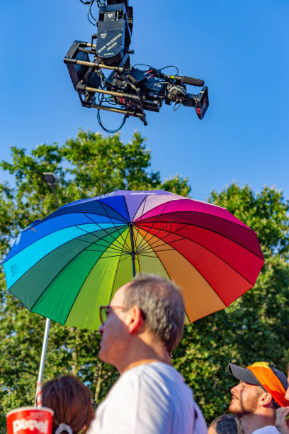 vista de ángulo bajo de la cámara de televisión sobre el hombre y el paraguas del arco iris en el desfile del orgullo madrileño - gay pride flag audio fotografías e imágenes de stock