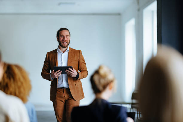 istock Smiling Business Man Holding A Digital Tablet And Talking To Audience During A Presentation 1444535570