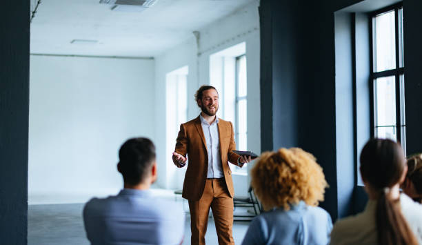 istock Smiling Business Man Holding A Digital Tablet And Talking To Audience During A Presentation 1444535581