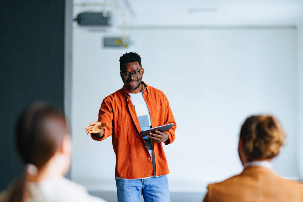istock Smiling Business Man Holding A Digital Tablet And Talking To Audience During A Presentation 1444535719