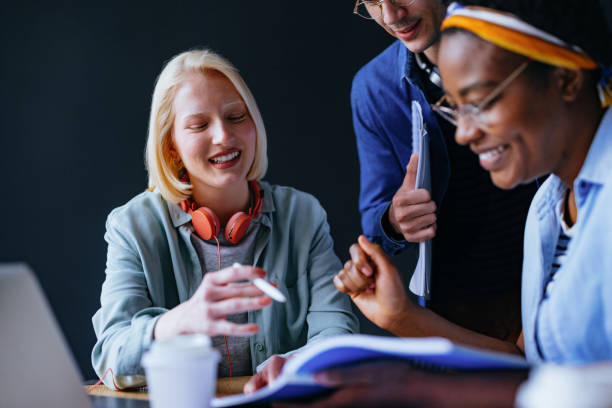 istock Smiling Woman Explaining New Lesson To Her Friends While Studying Together In The Library 1444535913