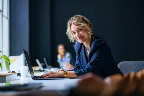 porträt einer glücklichen geschäftsfrau, die im büro sitzt - women computer business laptop stock-fotos und bilder