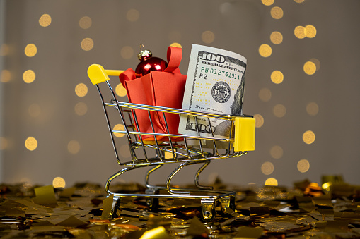 Cart with a shopping bag and hundred-dollar bills - gifts for Christmas and New Year.