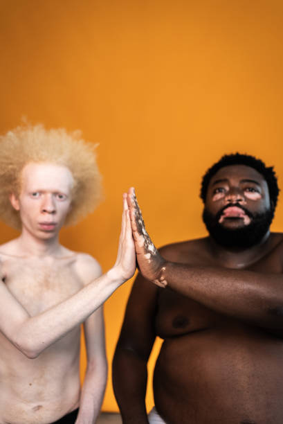 portrait of male friends doing a high five on an orange background - shirtless men bizarre male imagens e fotografias de stock