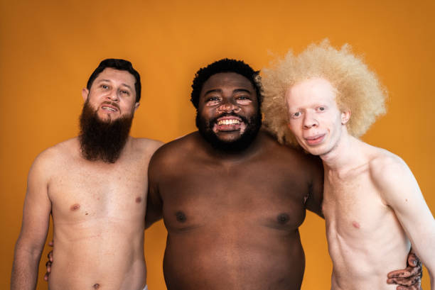 retrato de amigos varones abrazados sobre un fondo naranja - shirtless men bizarre male fotografías e imágenes de stock