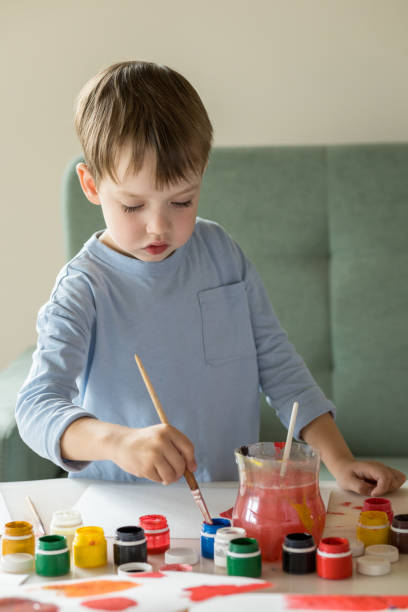 istock 5 year old white boy draws with a brush and paints on paper 1444539561