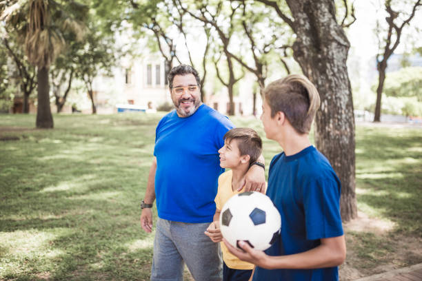 istock Father and two sons playing soccer in the park 1444545396