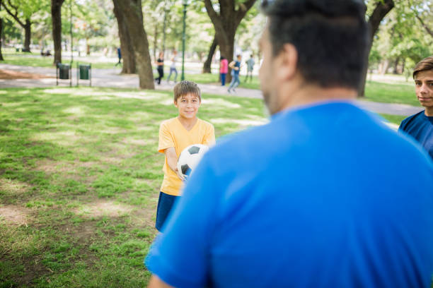 istock Father and two sons playing soccer in the park 1444546132