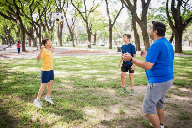 istock Father and two sons playing soccer in the park 1444546183