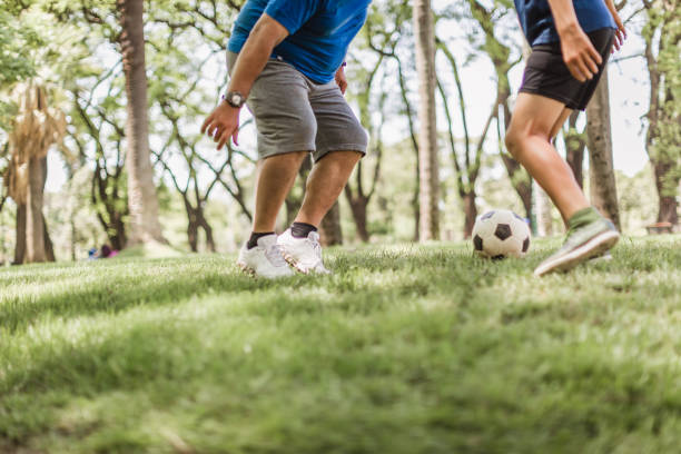 istock Father and two sons playing soccer in the park 1444546891