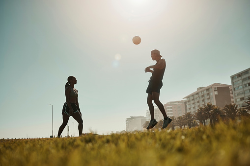 Man, woman and soccer ball play in grass park for exercise, training game and workout match. Fitness friends, football players and sports team playing in energy health wellness on Portugal city field