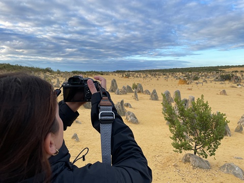 A woman taking a photo using her camera of the pinnacles in Western Australia