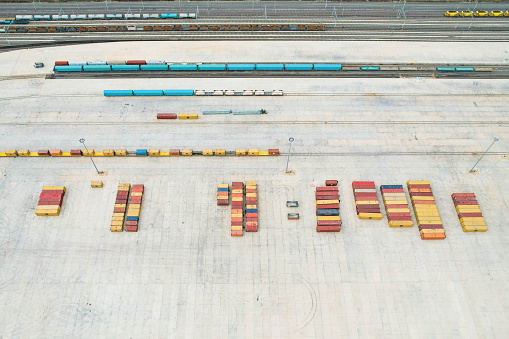 default\nDrone view of transport containers in logistics center lined up and train tracks on its side