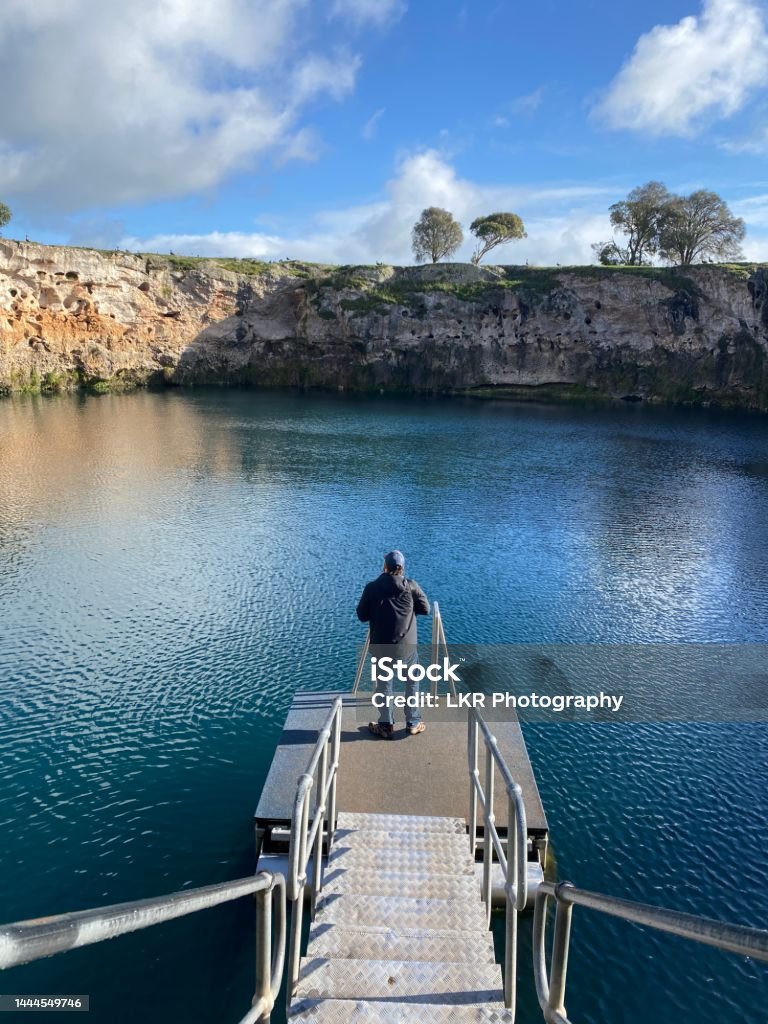 A man standing on a floating pontoon on little blue lake at Mount Gambier in South Australia Adult Stock Photo