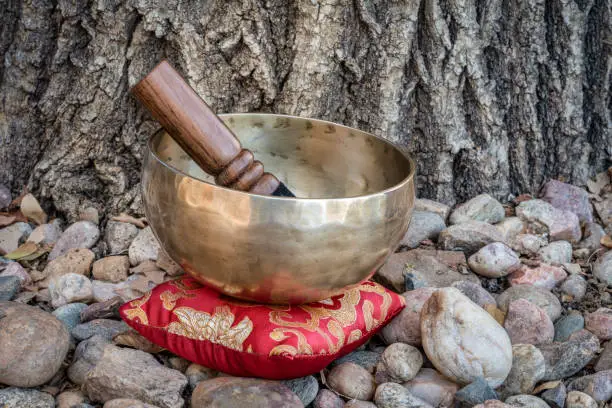 handmade Tibetan singing bowl with a mallet and cushion in outdoor setting, sound therapy for healing, relaxation and meditation