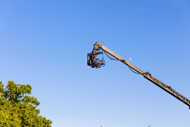 professional camcorder on a crane against a blue sky whit day moon. copy space. - filmando com guindaste imagens e fotografias de stock