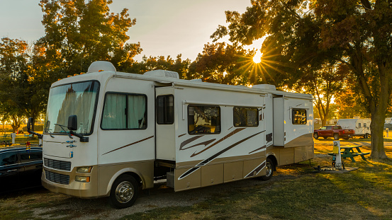 Camping at campsite in Rv motorhome with sunburst trees and grass