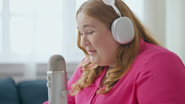 Positive plus-size woman laughing while recording her podcast, broadcasting show