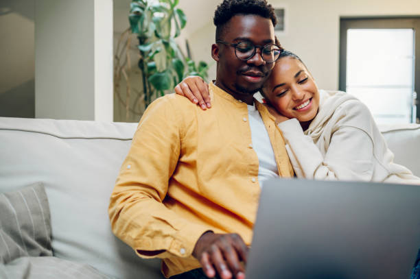istock Multiracial couple using laptop while sitting on a sofa at home 1444572975