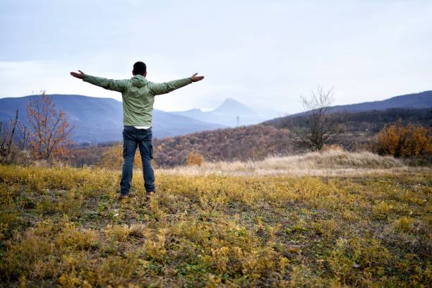 istock Hiker on the mountain with a stunning view stretching his hands 1444573392