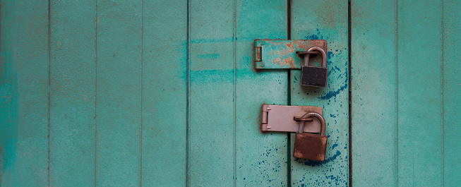 Two padlocks on turquoise vintage wooden door