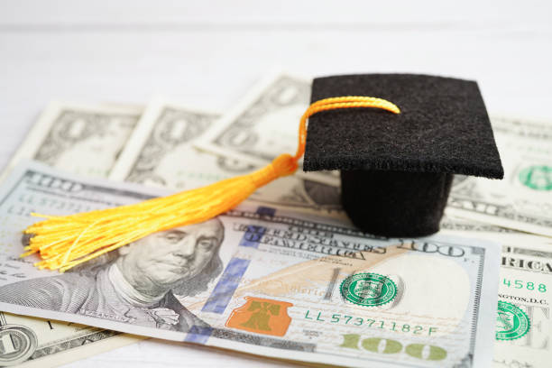 istock Graduation gap hat on US dollar banknotes money, Education study fee learning teach concept. 1444594682