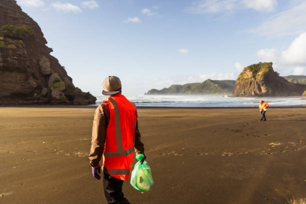 istock Two volunteer pick up trash on the beach. 1444594915