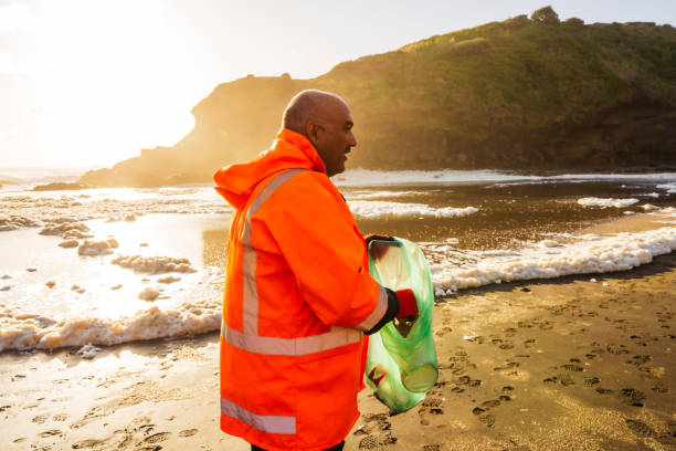 istock Man on beach at sunset, holding plastic rubbish. 1444594982