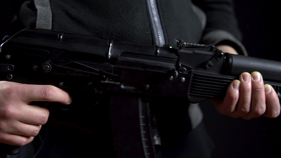 Un bandido se para con un arma en la mano sobre un fondo negro. Panorama de primer plano de izquierda a derecha. photo