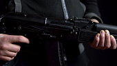 A bandit stands with a gun in hand on a black background. Close-up panorama from left to right.