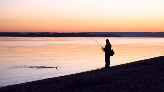 angler catching the fish during summer sunrise