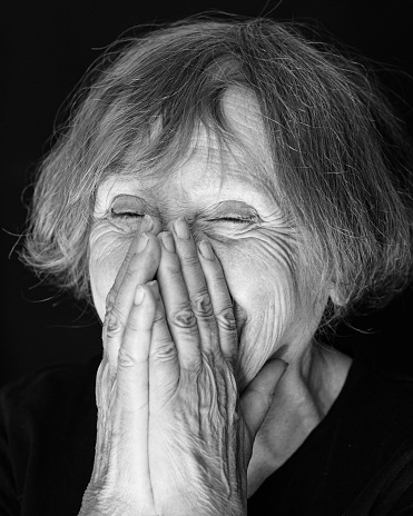 Portrait of senior laughing caucasian woman on black background. Close up, Black and white